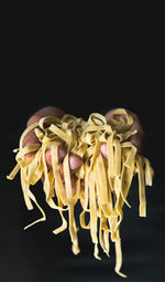 Cropped hand holding pasta dough against black background