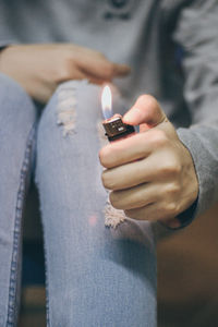 Midsection of man holding cigarette at home