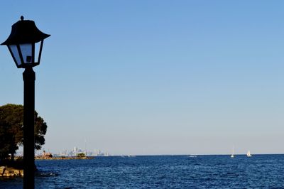 Street light by sea against clear sky
