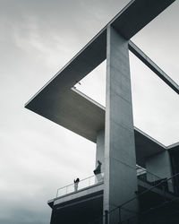 Low angle view of woman standing in balcony at building against sky