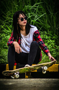 Woman in sunglasses with skateboard at park