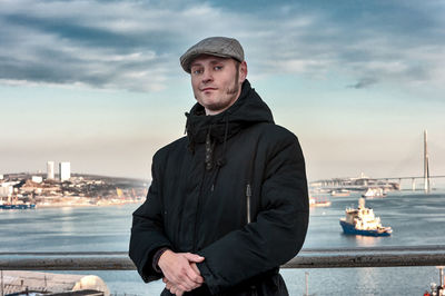 Young man standing in city against sky