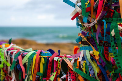 Close-up of colorful umbrellas hanging over sea against sky