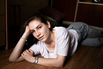 Portrait of young woman lying on table at home