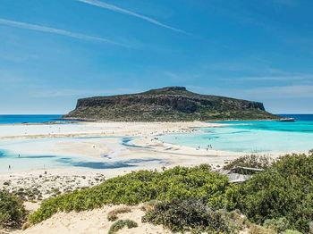 View of calm beach against blue sky