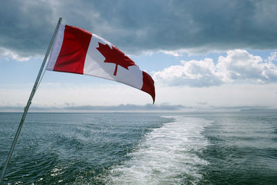 Red flag on sea against sky