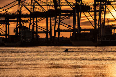 Silhouette people sitting on jet boat against harbor during sunset