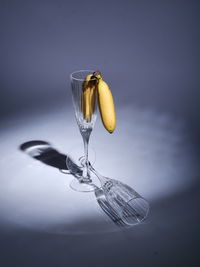 Close-up of water drop falling in glass against blue background