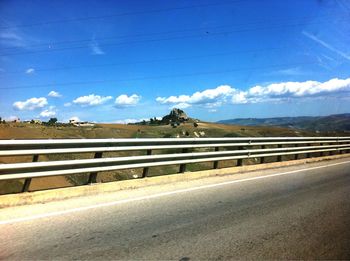 Road by landscape against blue sky