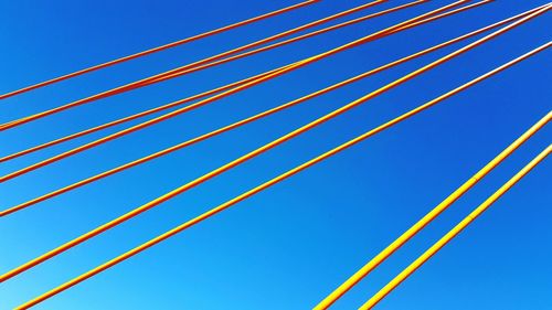 Low angle view of power lines against clear blue sky