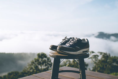 Empty chair on bench against sky