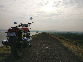 Bicycle on road amidst field against sky