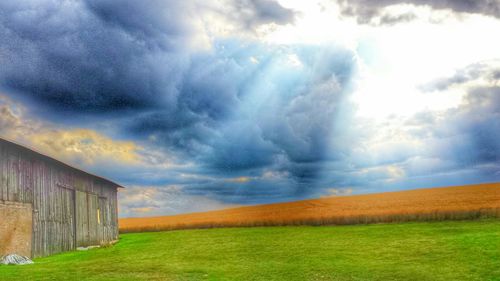 Scenic view of grassy field against cloudy sky