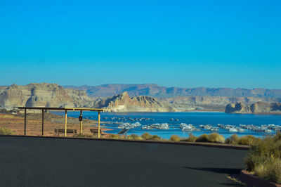 Road by sea against clear blue sky