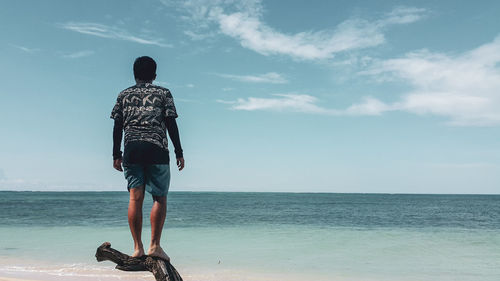 Rear view of man looking at sea against sky