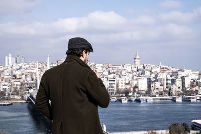 Rear view of man looking at sea against buildings in city