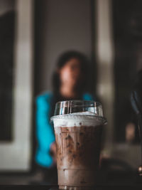 Close-up of woman drinking glass on table