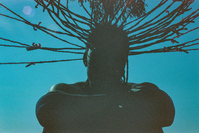 Low angle view of silhouette woman against blue sky