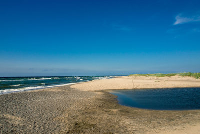 Scenic view of beach against blue sky