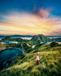 Rear view of woman on field against sky during sunset