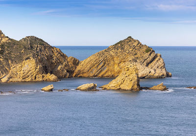 Scenic view of rock formation in sea against sky