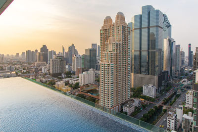 Modern buildings in city against sky during sunset