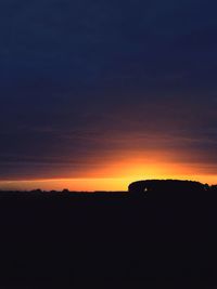 Scenic view of silhouette field against sky at sunset