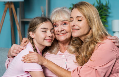 Portrait of mother and daughter embracing with grandmother at home