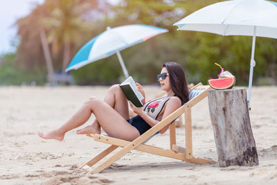 Young woman sitting on chair at beach