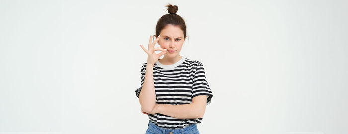 Portrait of young woman standing against white background