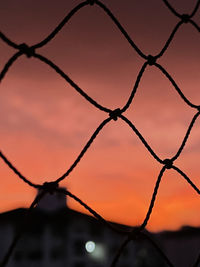 Full frame shot of chainlink fence against sky during sunset