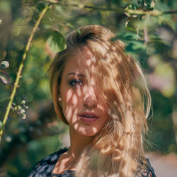 Portrait of young woman standing by tree