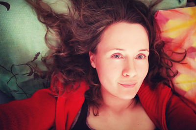 Close-up portrait of smiling young woman lying on bed