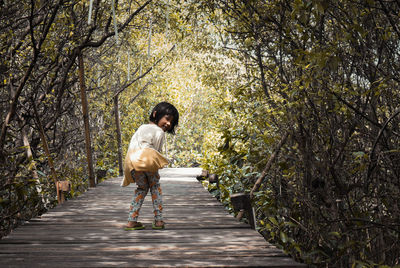 Rear view of man walking on footpath in forest