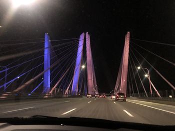 Illuminated bridge seen through car windshield at night