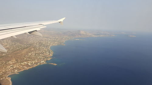 Aerial view of aircraft wing over sea against sky
