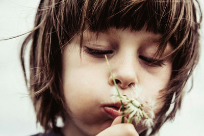 Close-up of boy blowing dandelion