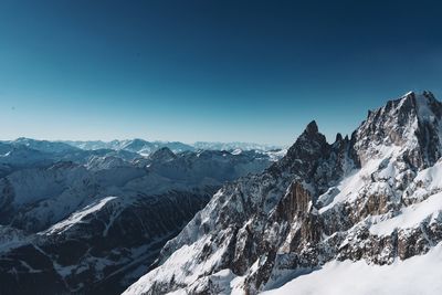 Scenic view of snowcapped mountains against clear blue sky