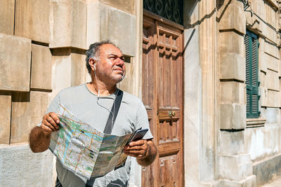 Tourist man on the street looking map wondering where he should go. urban traveling leisure.