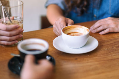 Midsection of woman holding coffee cup on table