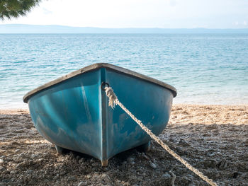 Boat moored on beach against sky