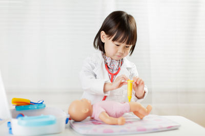 Cute doctor playing with toys on table