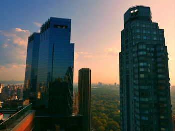 Modern buildings in city against sky during sunset