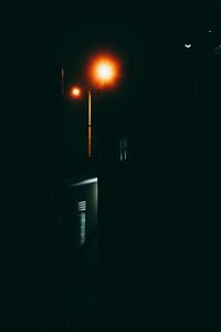 Illuminated street light against building at night