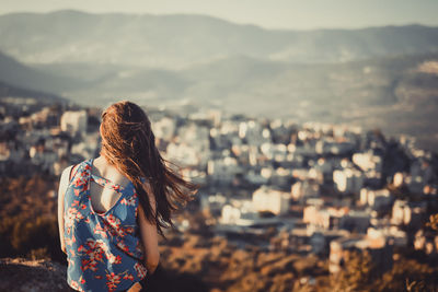 Rear view of woman standing against sea and cityscape