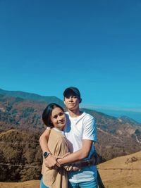 Young couple standing on mountain against sky