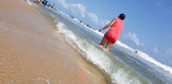 Rear view of woman on beach against sky