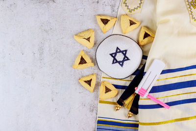 Jewish carnival purim celebration on hamantaschen cookies, noisemaker and mask with parchment