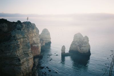 Rock formations by sea against sky on a foggy morning. shot on 35mm kodak portra 400 film.