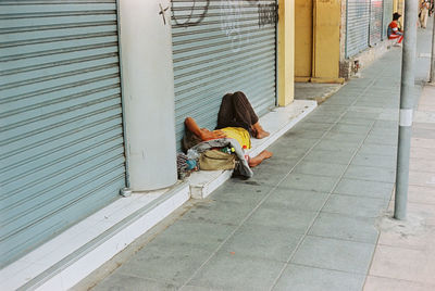 Woman sitting on footpath